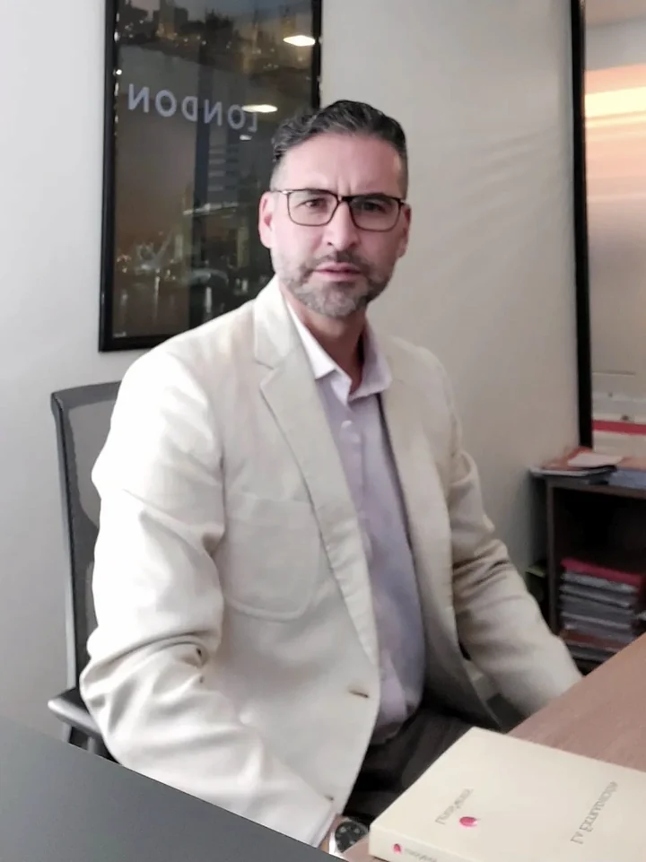 Federico A. Borzi Cirilli sentado en su oficina, junto a su libro